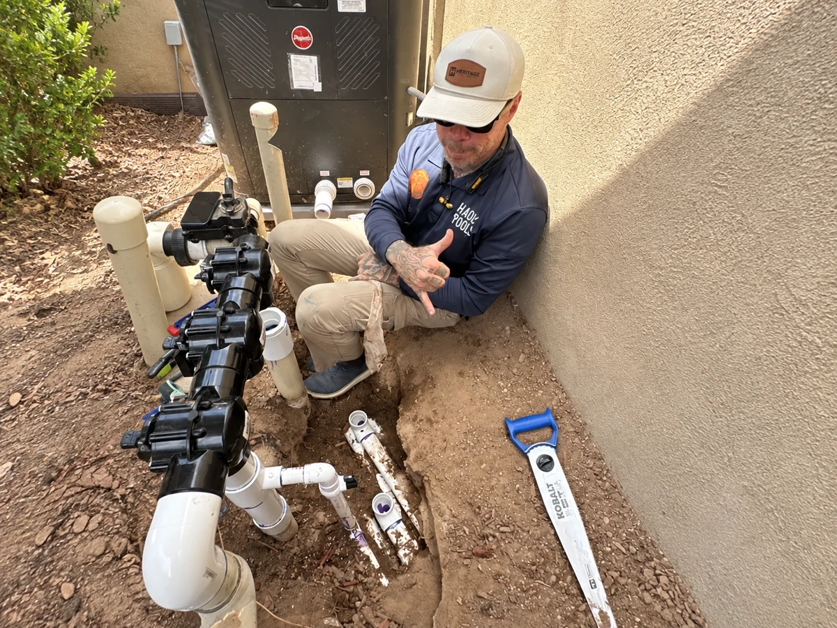 Paule smiling and giving a thumbs-up beside an underground plumbing repair