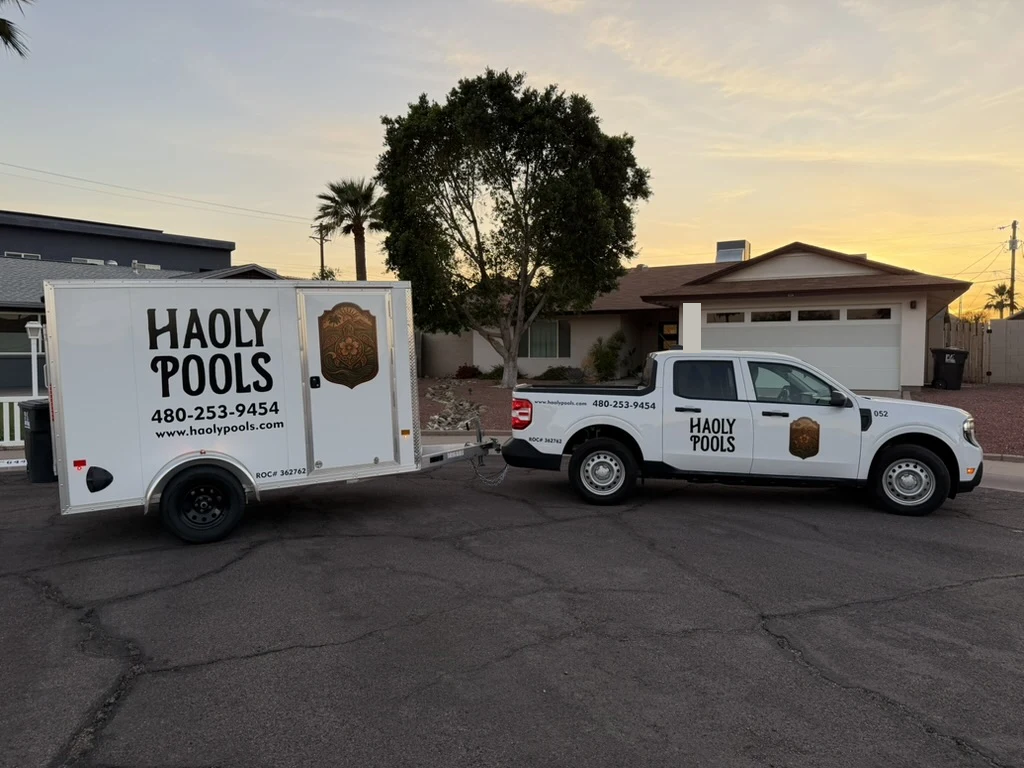 Side view of a Haoly Pools truck and trailer at sunset